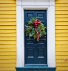 Blue door with white frame as entry for yellow home